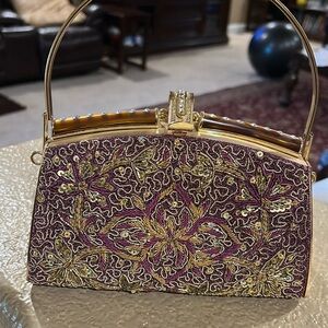 Elegant gold and maroon clutch with gold handle and gold chain